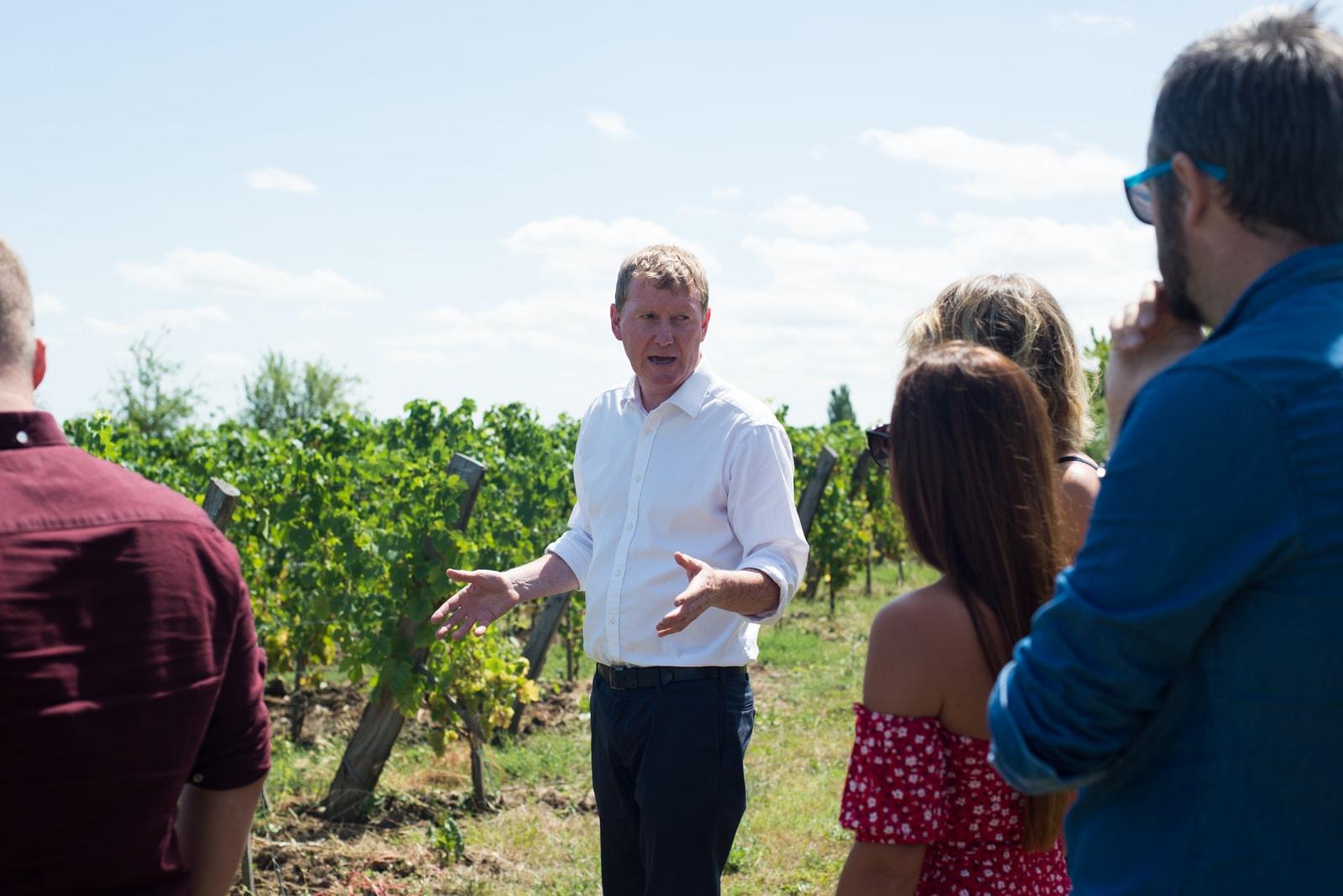 A winemaker explaining the vines to a small tour group