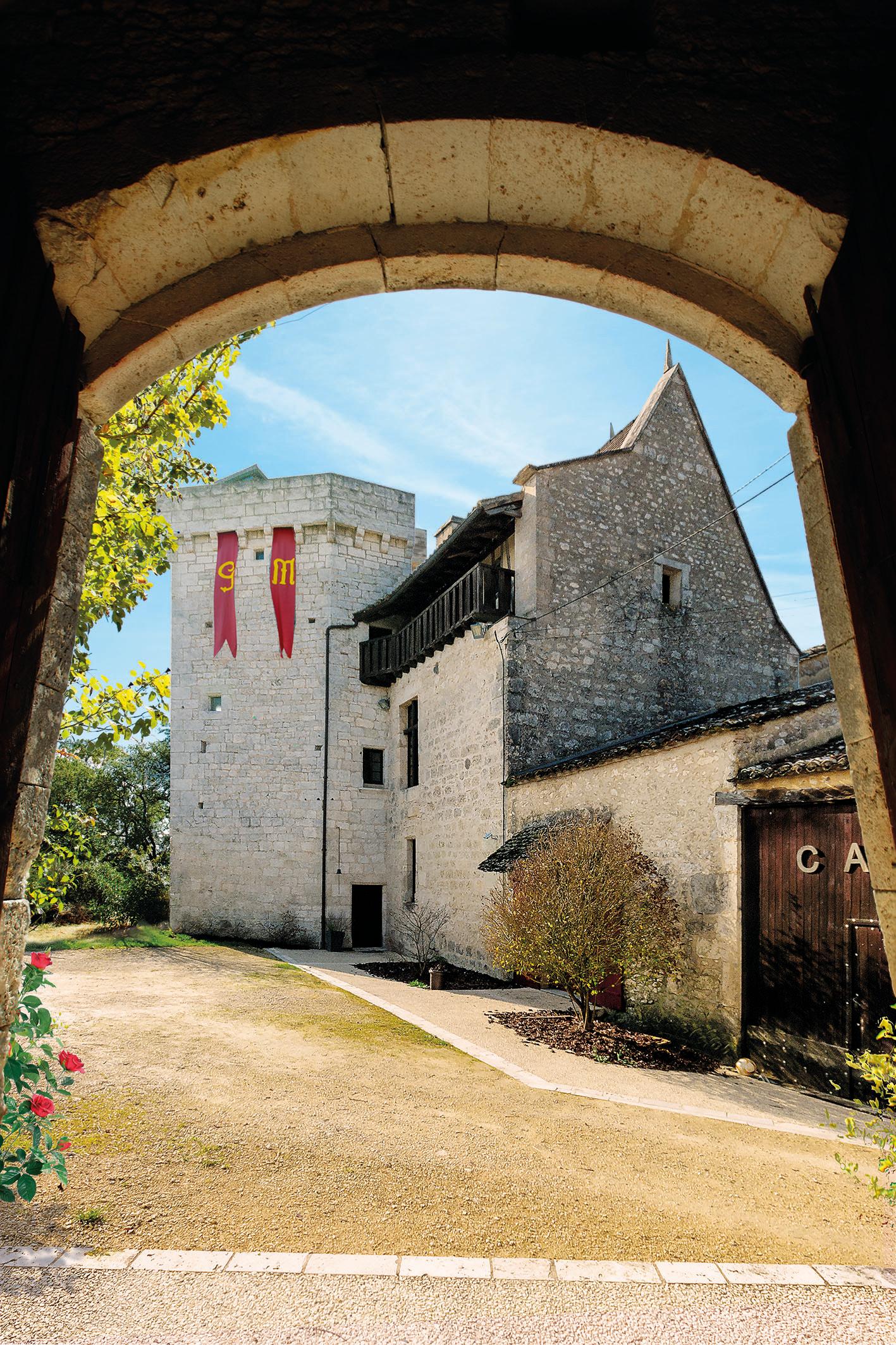 La Grande Maison’s stone buildings and tower viewed through a stone archway