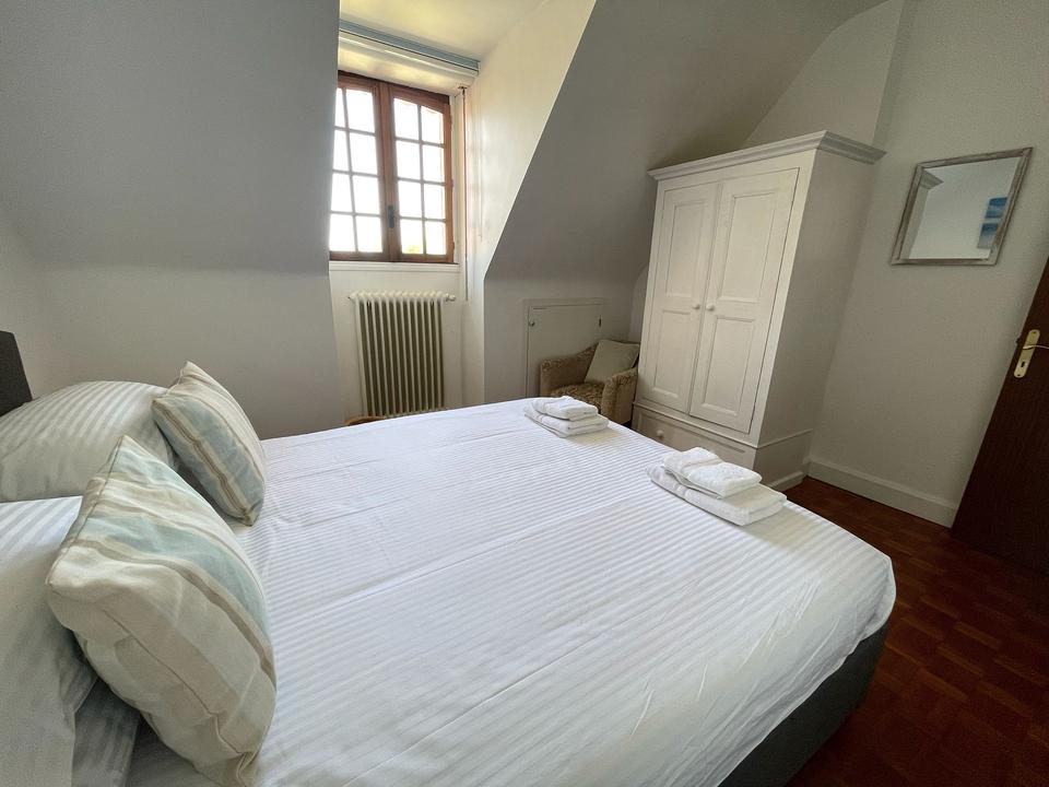 Doppelbett unter einer Dachschräge mit Fenster und hohem weißem Kleiderschrank