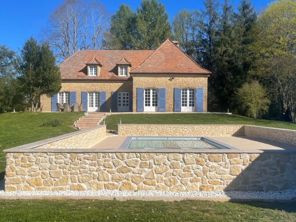 Steinhaus mit blauen Fensterläden oberhalb des Pools