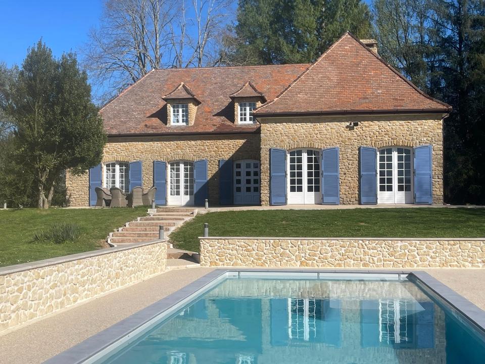 Haus und blaue Fensterläden spiegeln sich im Pool