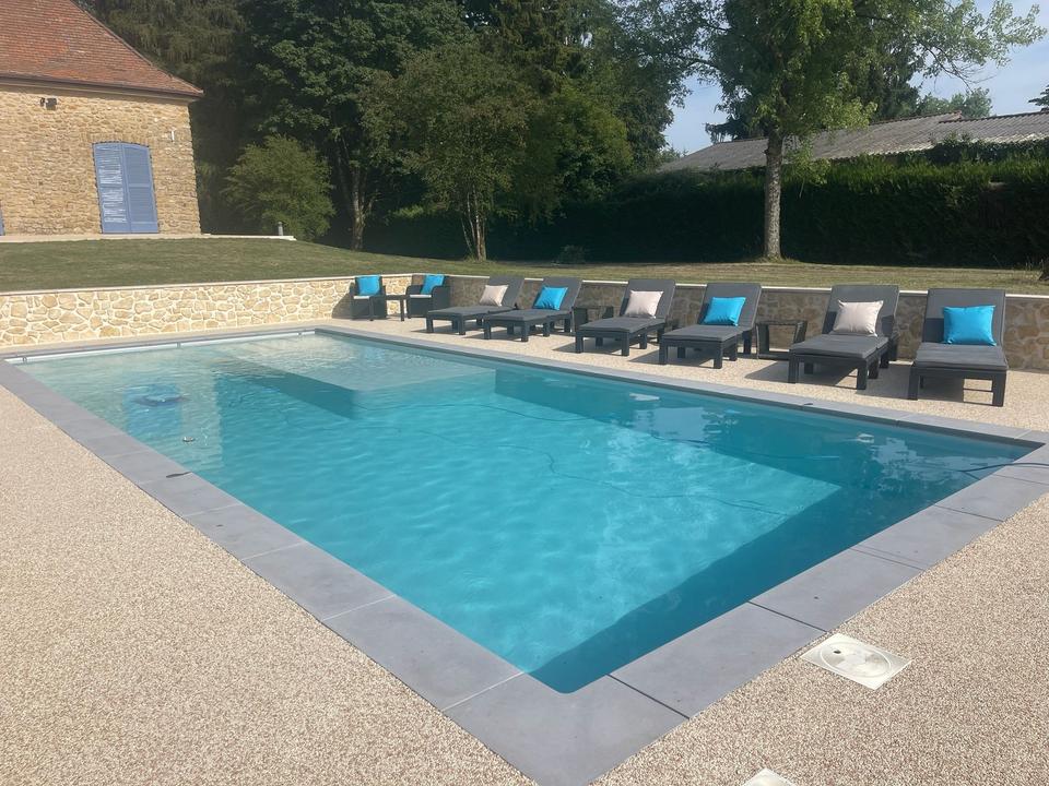 Pool und Sonnenliegen an der Gartenmauer